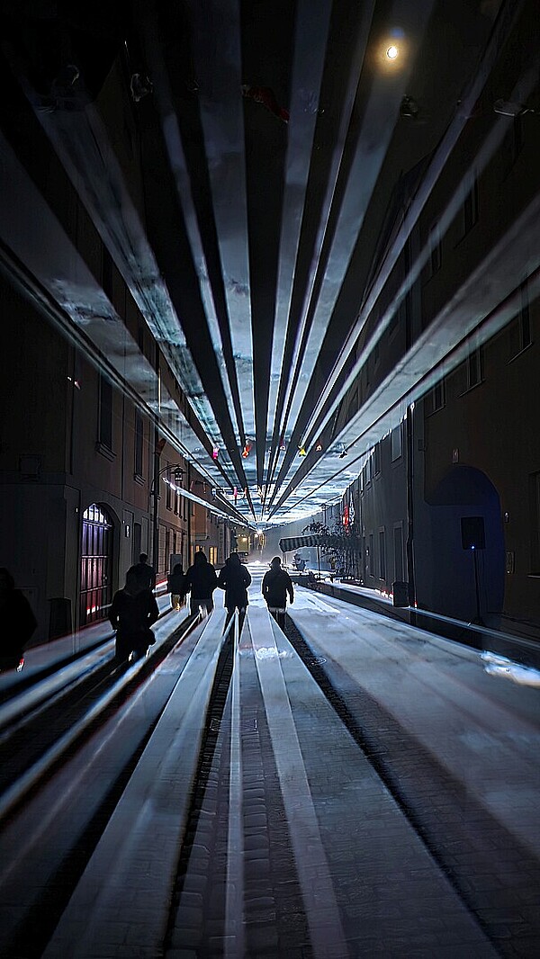 Besucher werfen Schatten in die Laserlichtkunst der Donaugasse Vilshofen. 