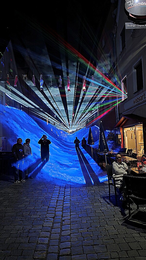 Besucher genießen einen Abend mit Lichtkunst Bewegung und Begegnung in der Donaugasse. 